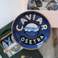 Blue and gold 'Caviar Osetra' trinket dish on a white surface with a blurred background