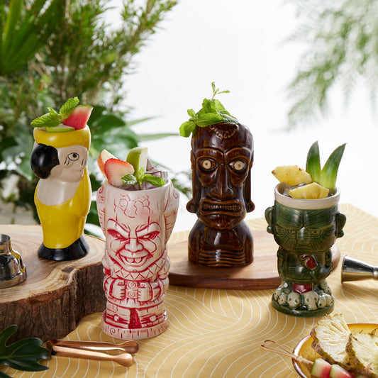 4 different tiki mugs with drinks on a table with a natural background