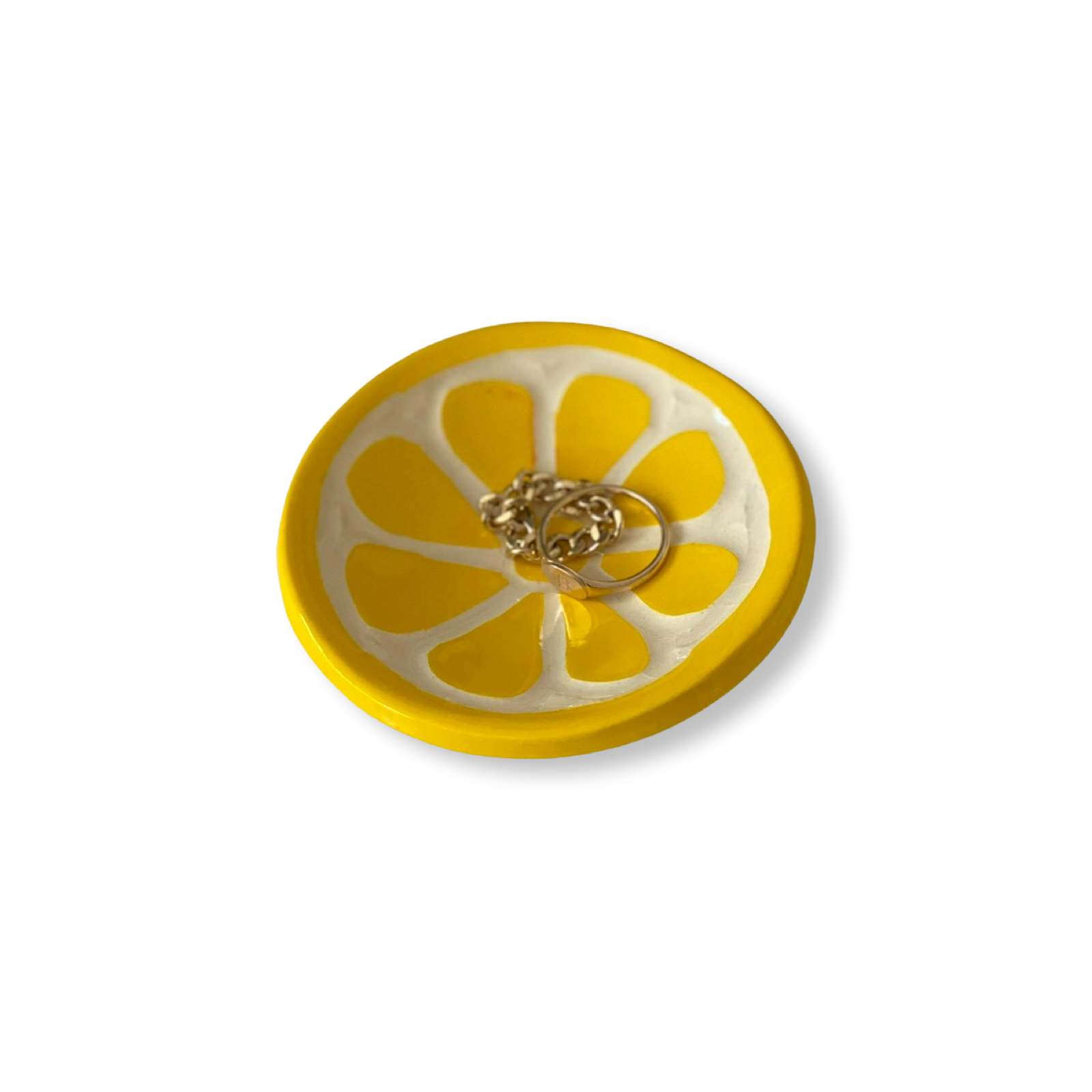 Yellow lemon sliced-shaped dish with a gold ring on a white background