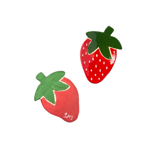 Two strawberry trinket dishes with green leaves on a white background