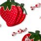 Two strawberry-shaped plates with candies on a white background