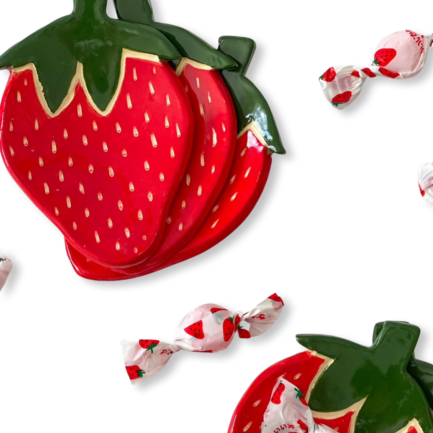 Two strawberry-shaped plates with candies on a white background