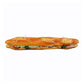 Wax candle shaped like a whole baguette sliced lengthwise and made into a hearty sandwich with many fillings. View from the side.
