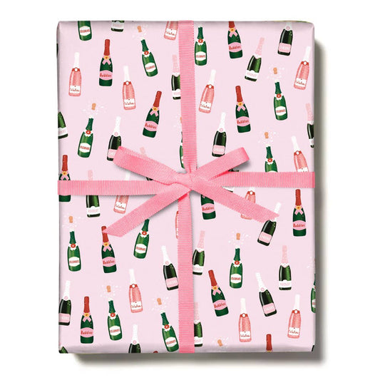 wrapping paper with a light pink background and repeated pattern features different bottles of bubbly 