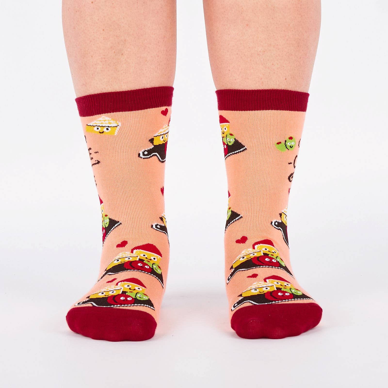 Pair of pink and burgundy socks with cartoon illustration of a charcuterie board design and text (char-CUTE-erie) on a white background