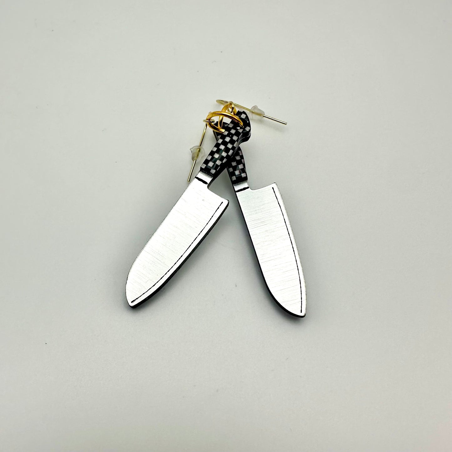 2 earrings that look like knives. The handles are black and white checker. 