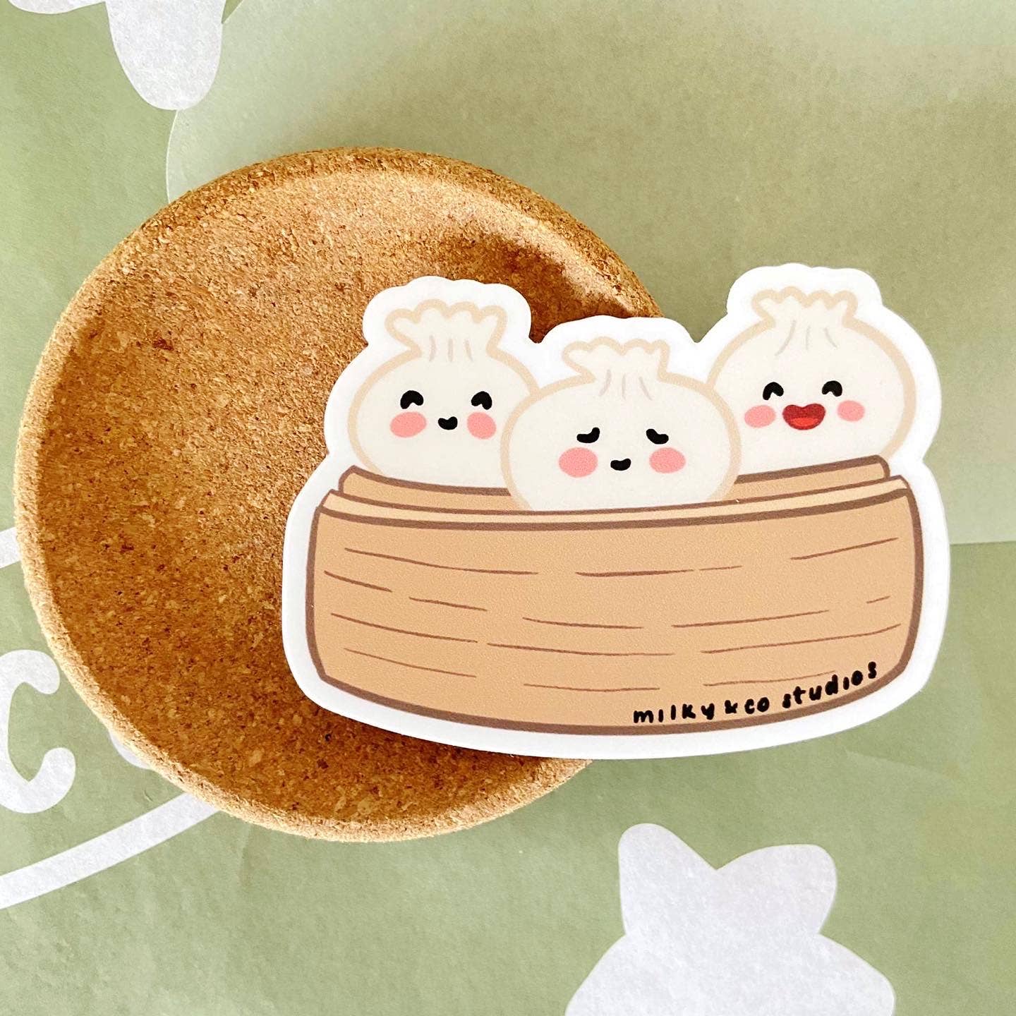 sticker of 3 dim sums inside a bamboo steamer 