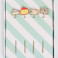 Set of four cheese-themed cocktail picks on a green and white striped background