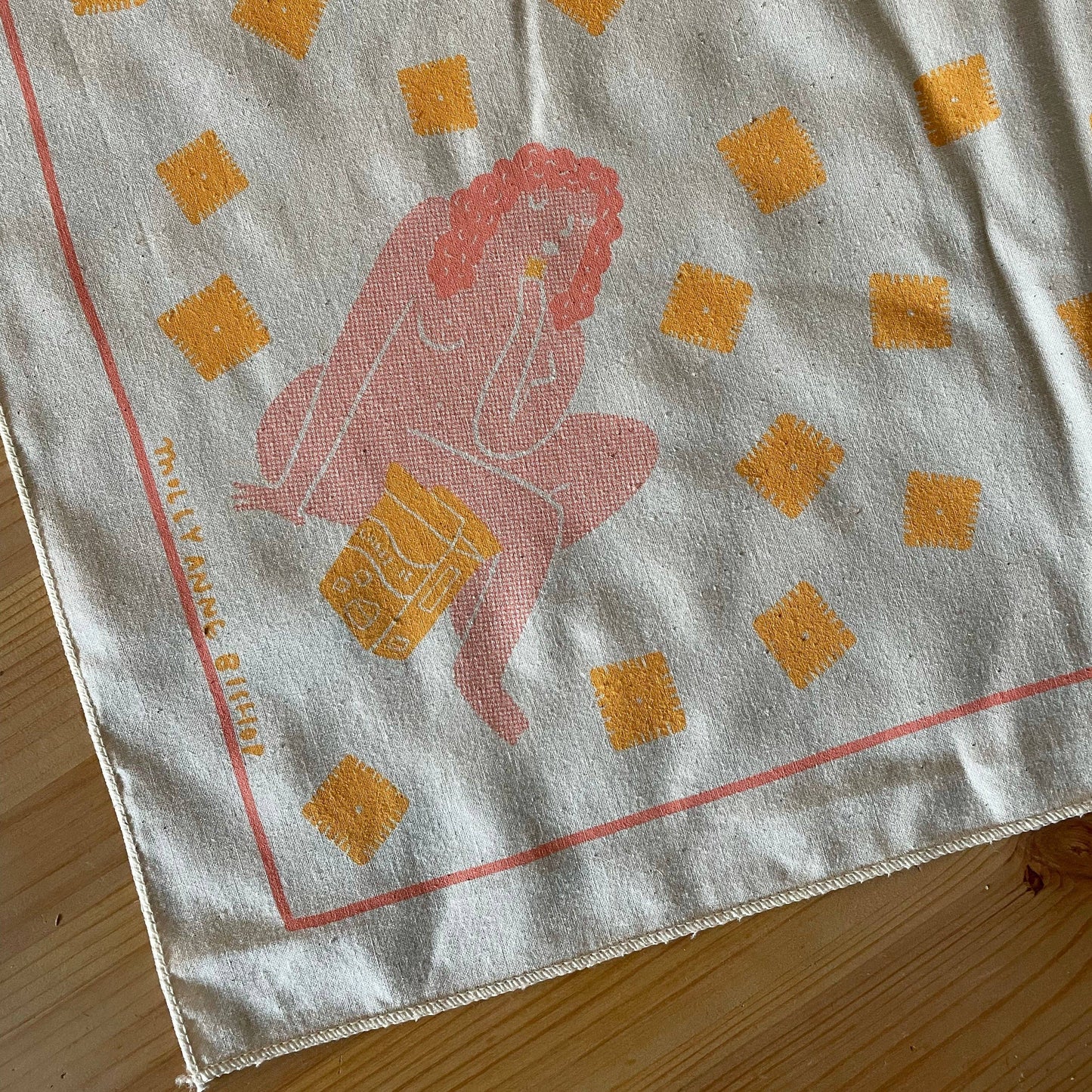 Fabric with a printed design of a woman and cheez it shapes on a wooden surface