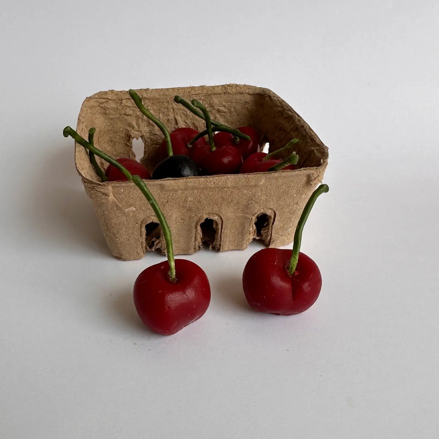 Realistic Cherry candles in a pulp fruit basket.