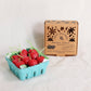 Box of Happy Organics birthday candles shaped like cherries next to a container of small red fruits.