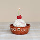 Ice cream bowl with cherry shaped candle on a checkered tablecloth