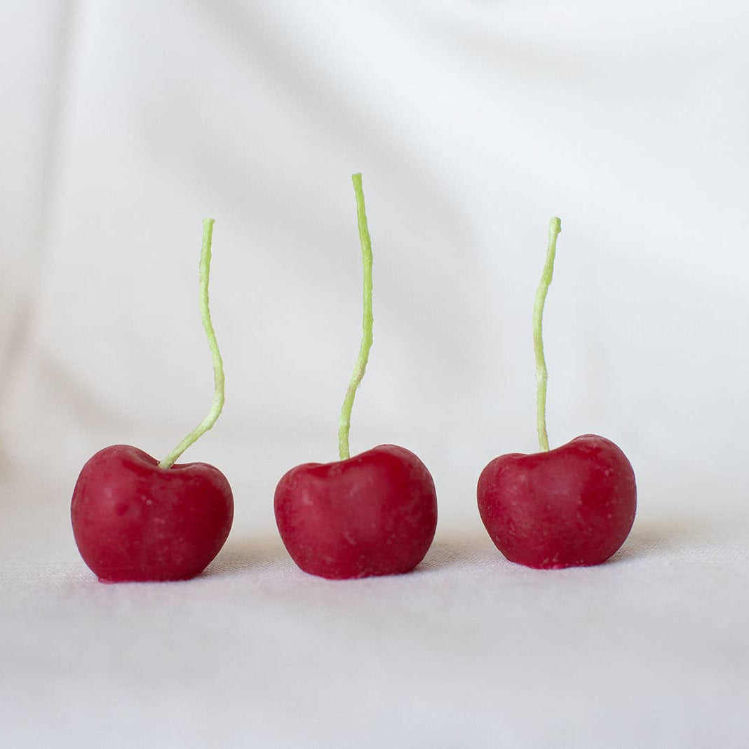 Three cherries lined up on a white background