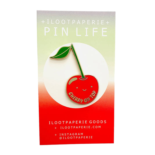 Cherry-themed enamel pin on a colorful card with 'ILOOTPAPERIE' branding.