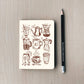 Notebook with coffee-themed illustrations on a wooden surface with a pencil next to it.