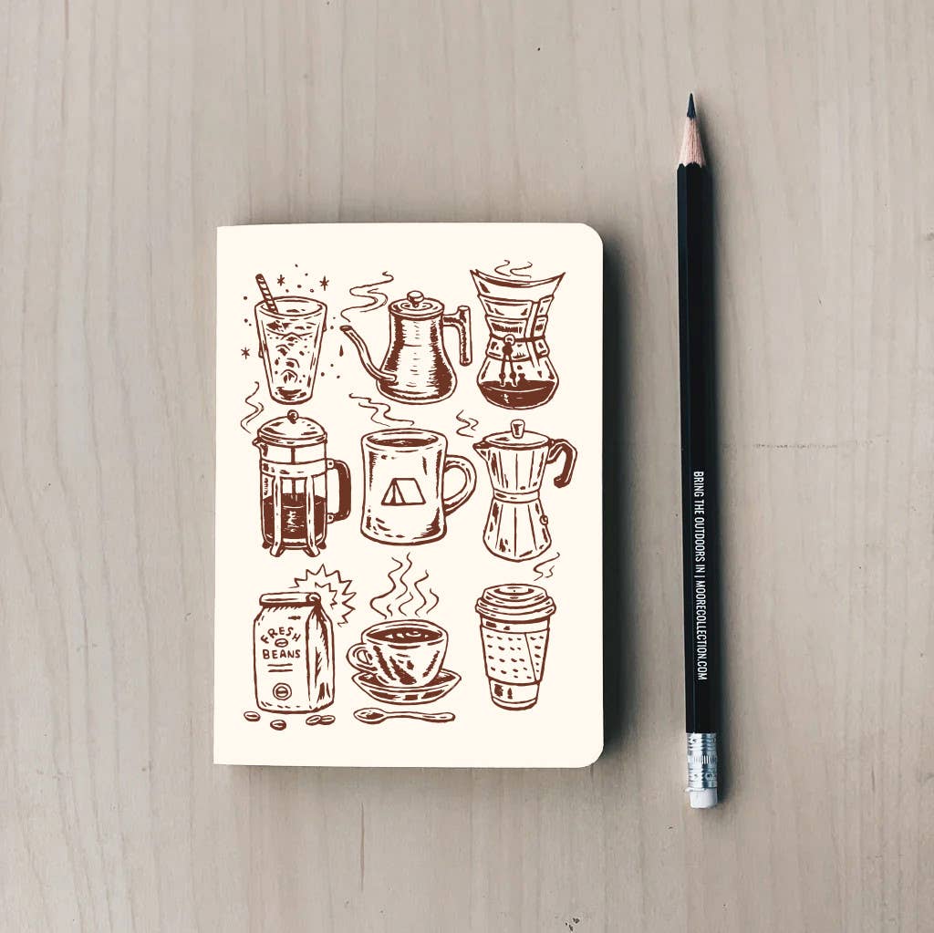 Notebook with coffee-themed illustrations on a wooden surface with a pencil next to it.