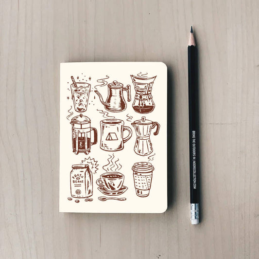 Notebook with coffee-themed illustrations on a wooden surface with a pencil next to it.
