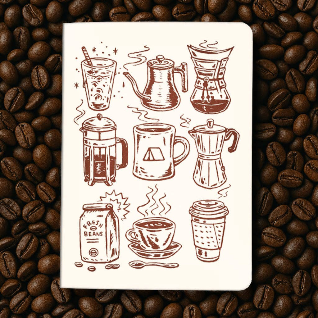 Notebook with coffee-themed illustrations on a bed of coffee beans