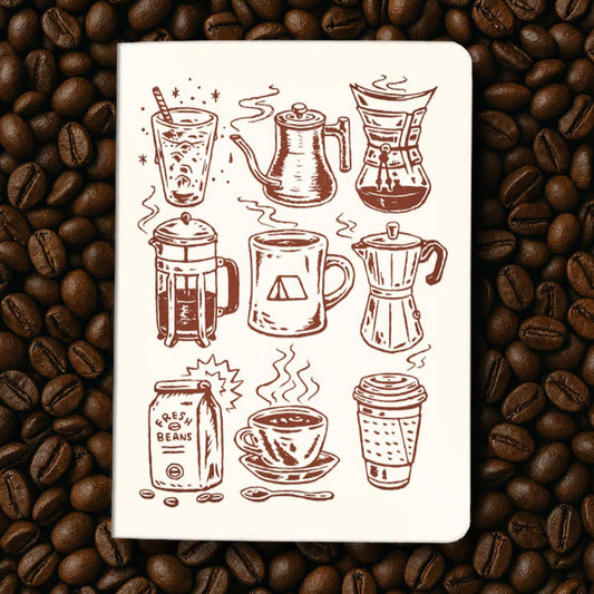Notebook with coffee-themed illustrations on a bed of coffee beans