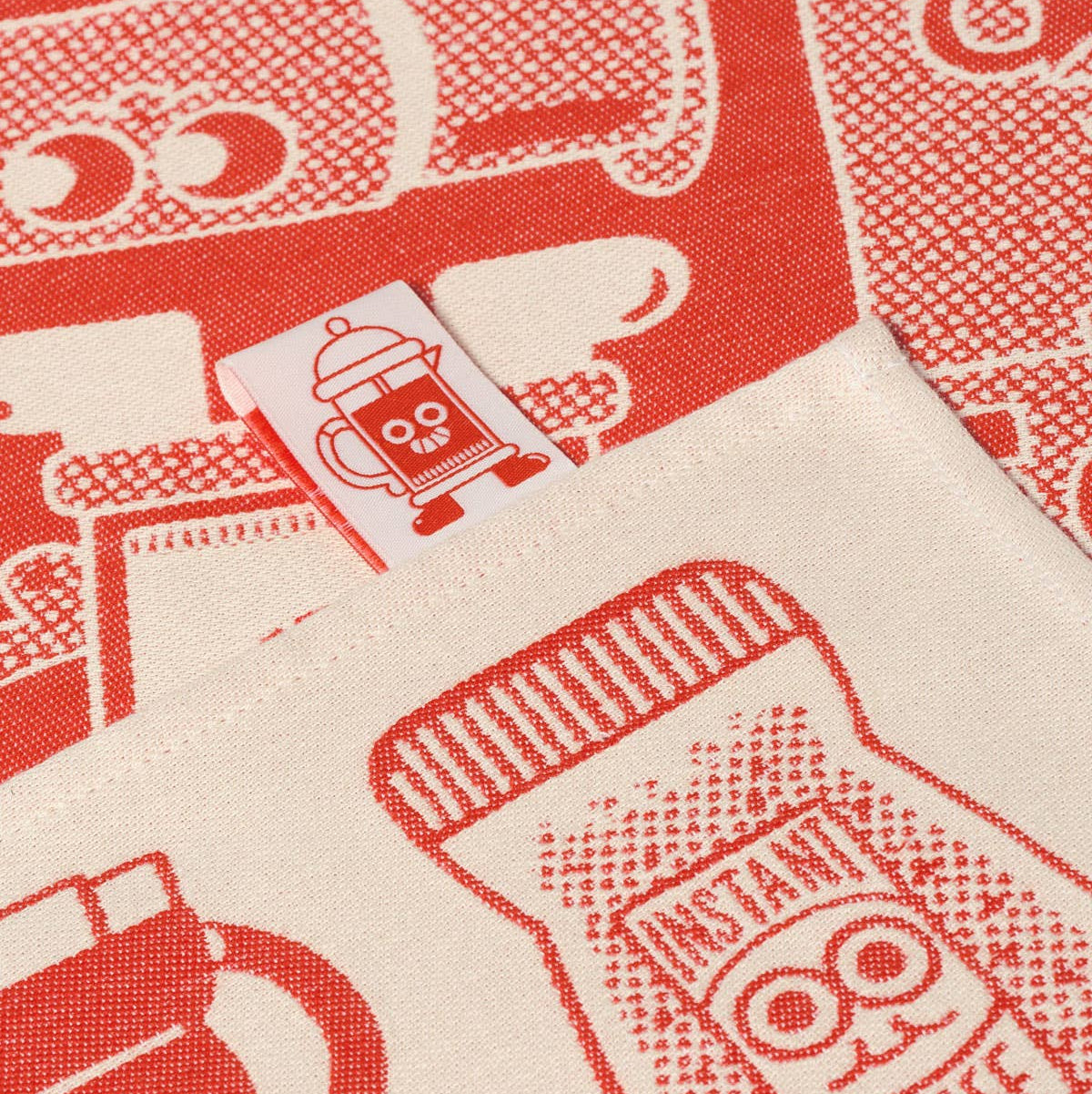 Close-up of a red and white patterned fabric with coffee-themed designs.