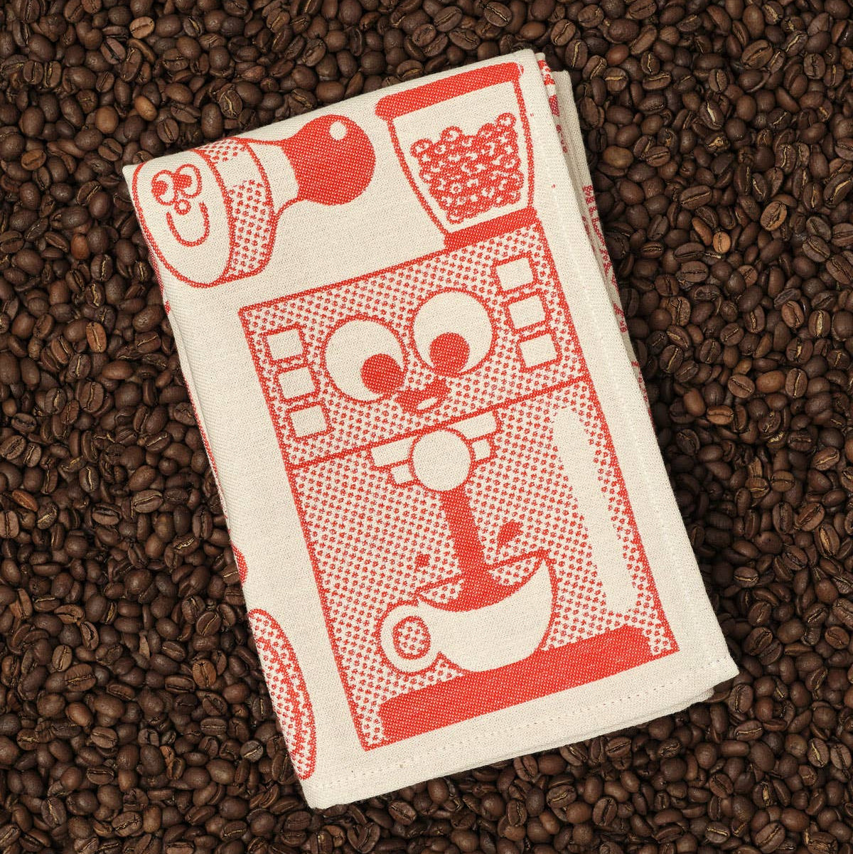Folded towel with red graphics on a bed of coffee beans