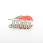 Hair clip with coral-colored plastic base made to look like a crab and silver comb teeth on a white background