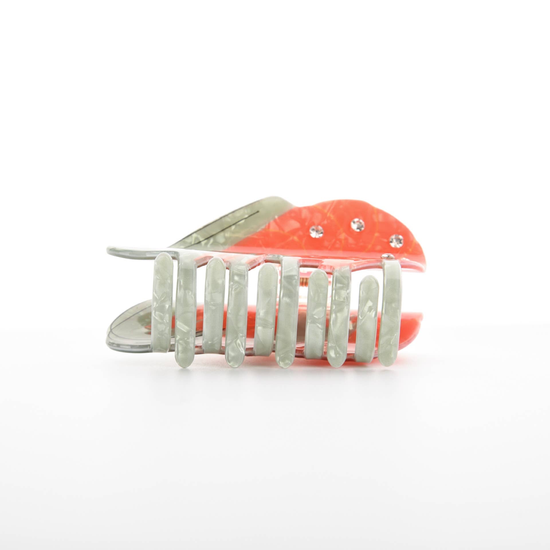 Hair clip with coral-colored plastic base made to look like a crab and silver comb teeth on a white background