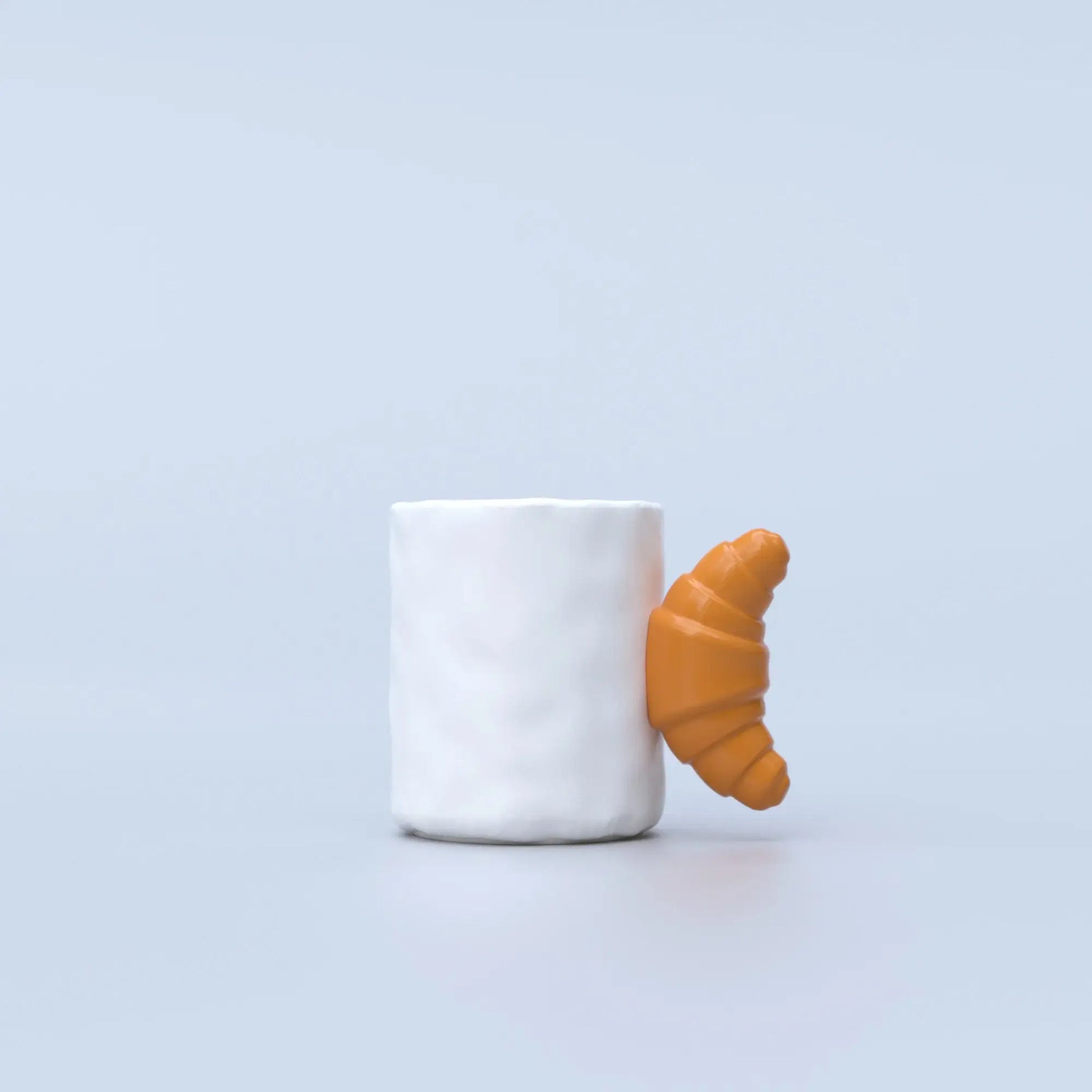 white ceramic mug with a brown handle shaped like a croissant 