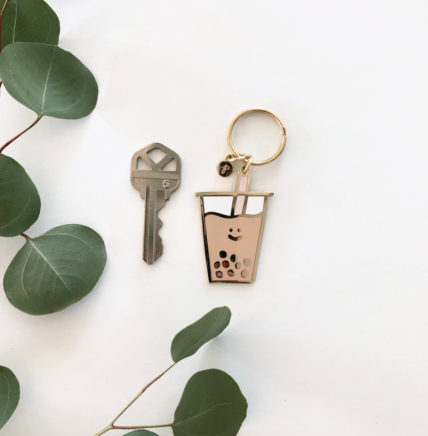 Photo of Boba Keychain with teal colored straw. Shown next to a house key for size.