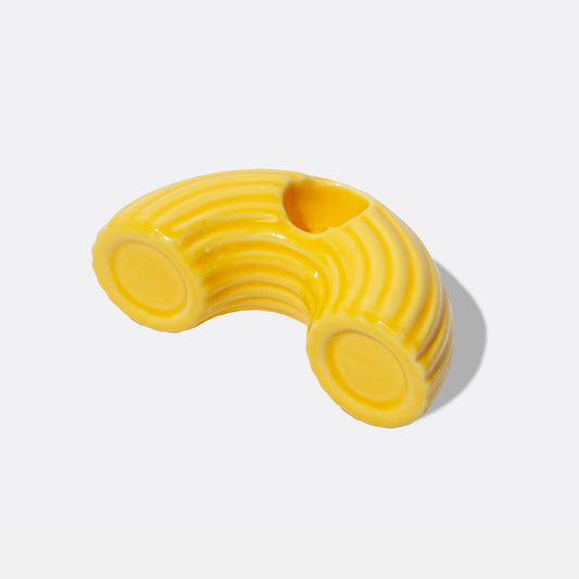 Yellow macaroni pasta shaped ceramic candle holder on a white background