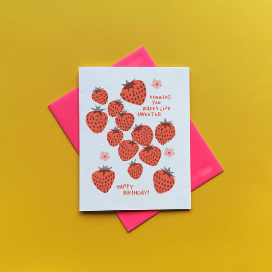 Greeting card -- mostly white with red strawberries and pink flowers all over. text reads "Knowing you makes life sweeter. Happy birthday!" 