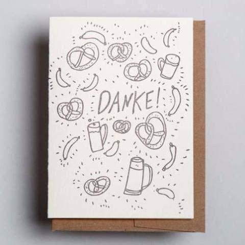 white greeting card with embossed pretzels, sausages and beer mugs on it. Embossed text also reads "Danke!" 