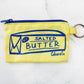 light yellow coin/card purse with a blue zipper, stick of butter printed in blue ink on front. Includes attached keyring 