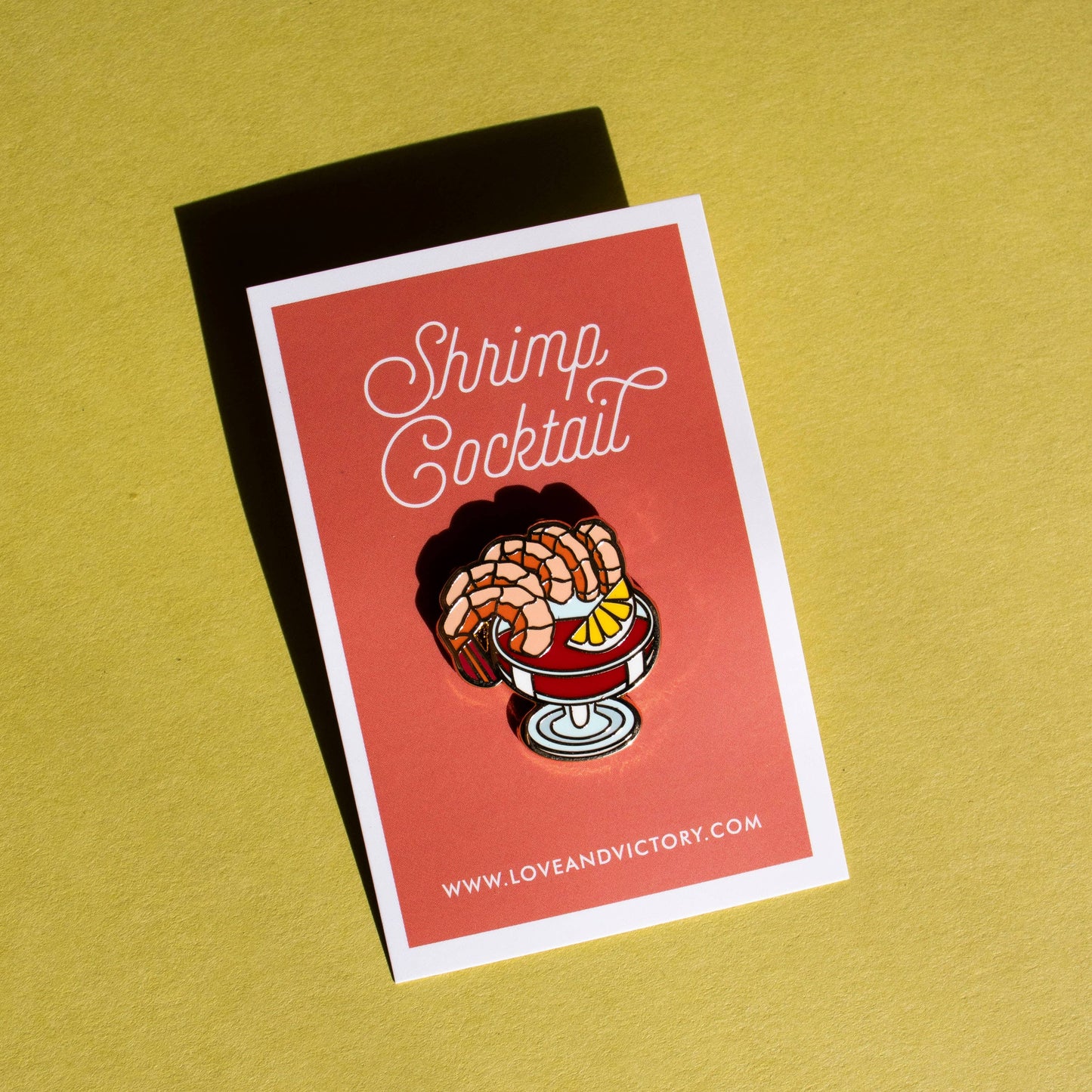 Shrimp cocktail lapel pin on red card backing that reads "Shrimp Cocktail" 