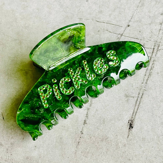 Green sparkly hair clip with "Pickles" written in rhinestones.