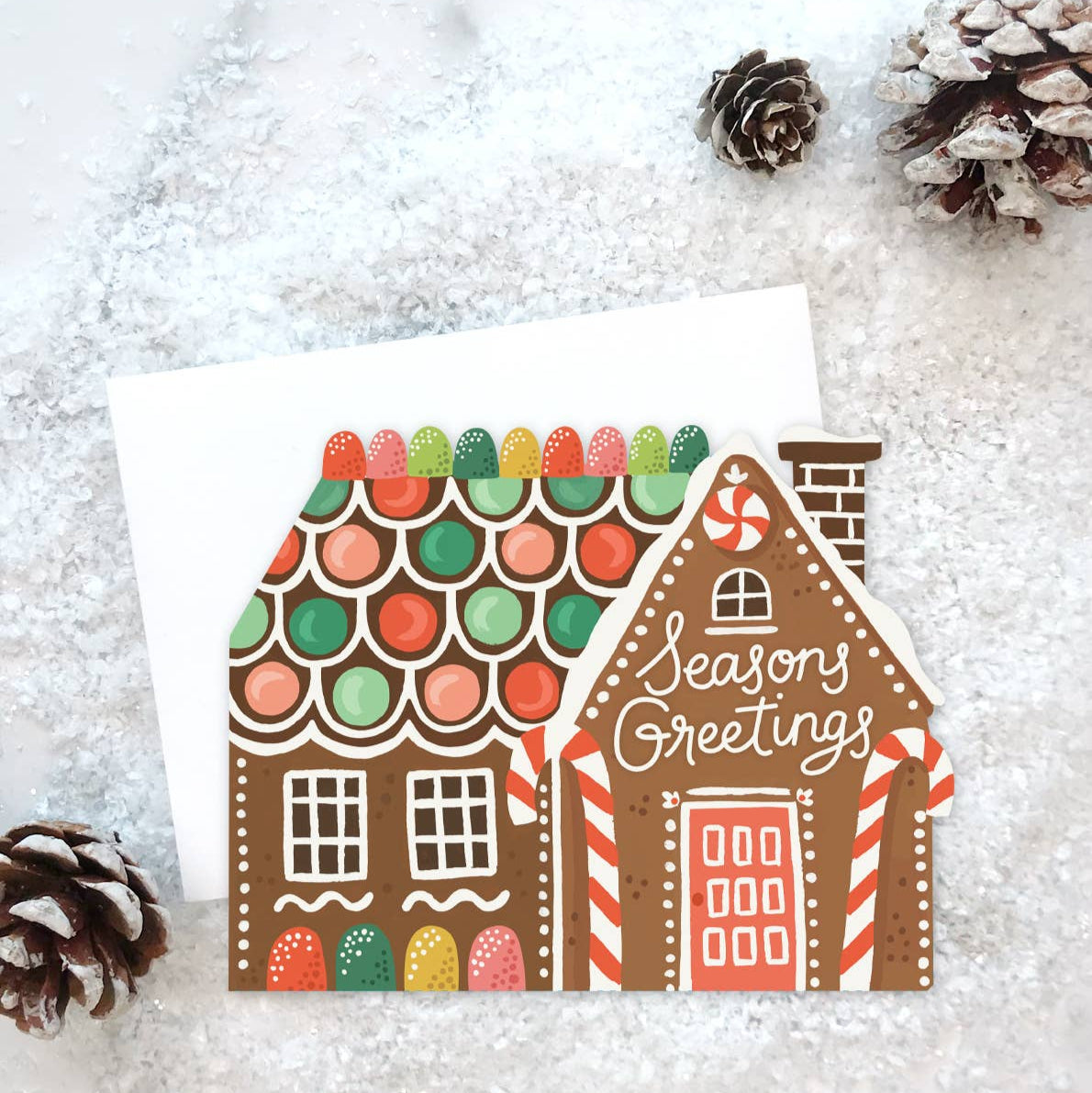 Greeting card with a gingerbread house design on a snowy background