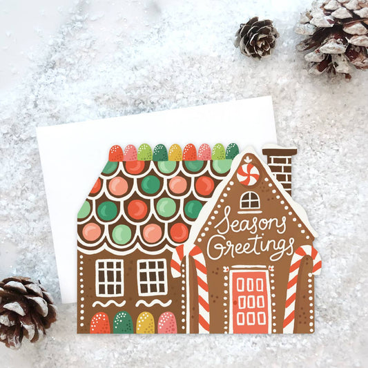 Greeting card with a gingerbread house design on a snowy background
