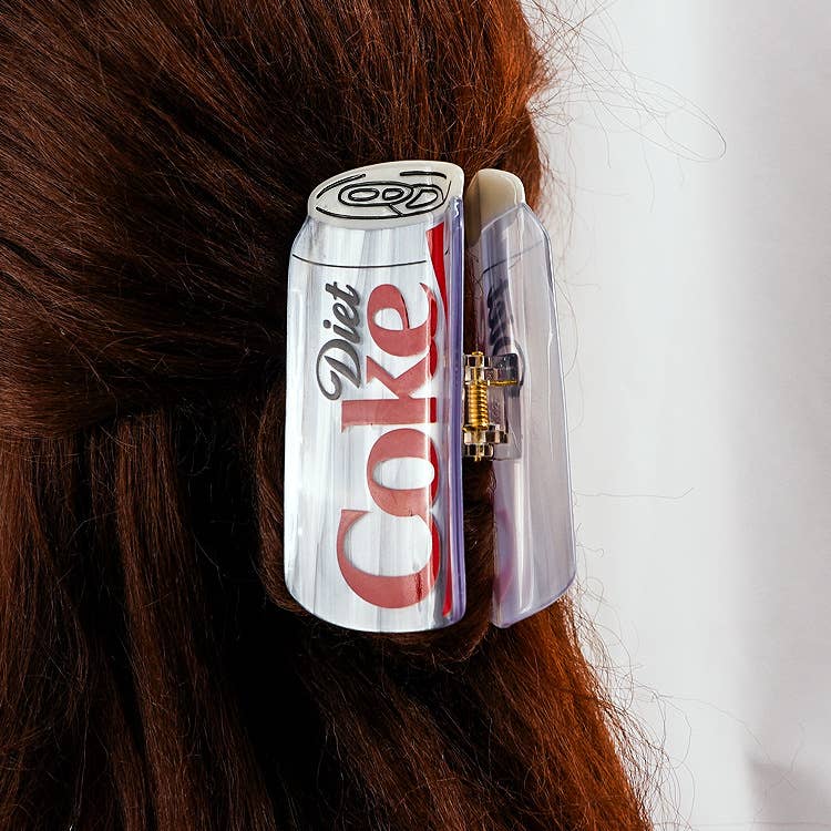 Diet Coke can-shaped hair clip on a person's hair against a white background