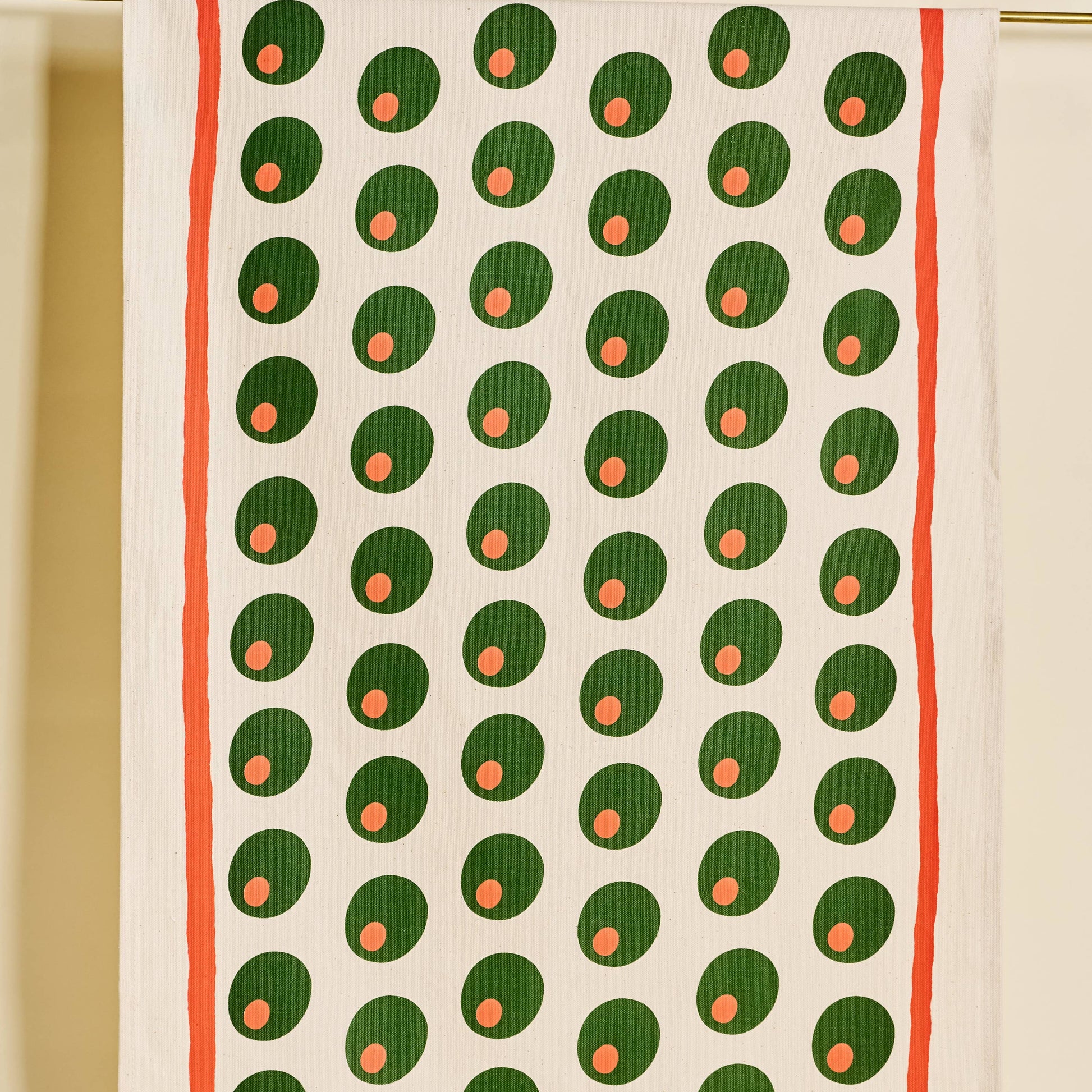 Tea towel with pimento stuffed green olives pattern on a white background with a red line border along edges