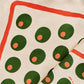 Fabric with pimento stuffed green olives pattern on a beige background and red line border along edge