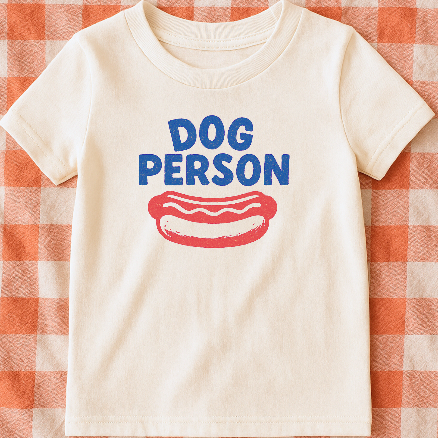 White t-shirt with 'DOG PERSON' and a hot dog graphic on a red and white checkered background