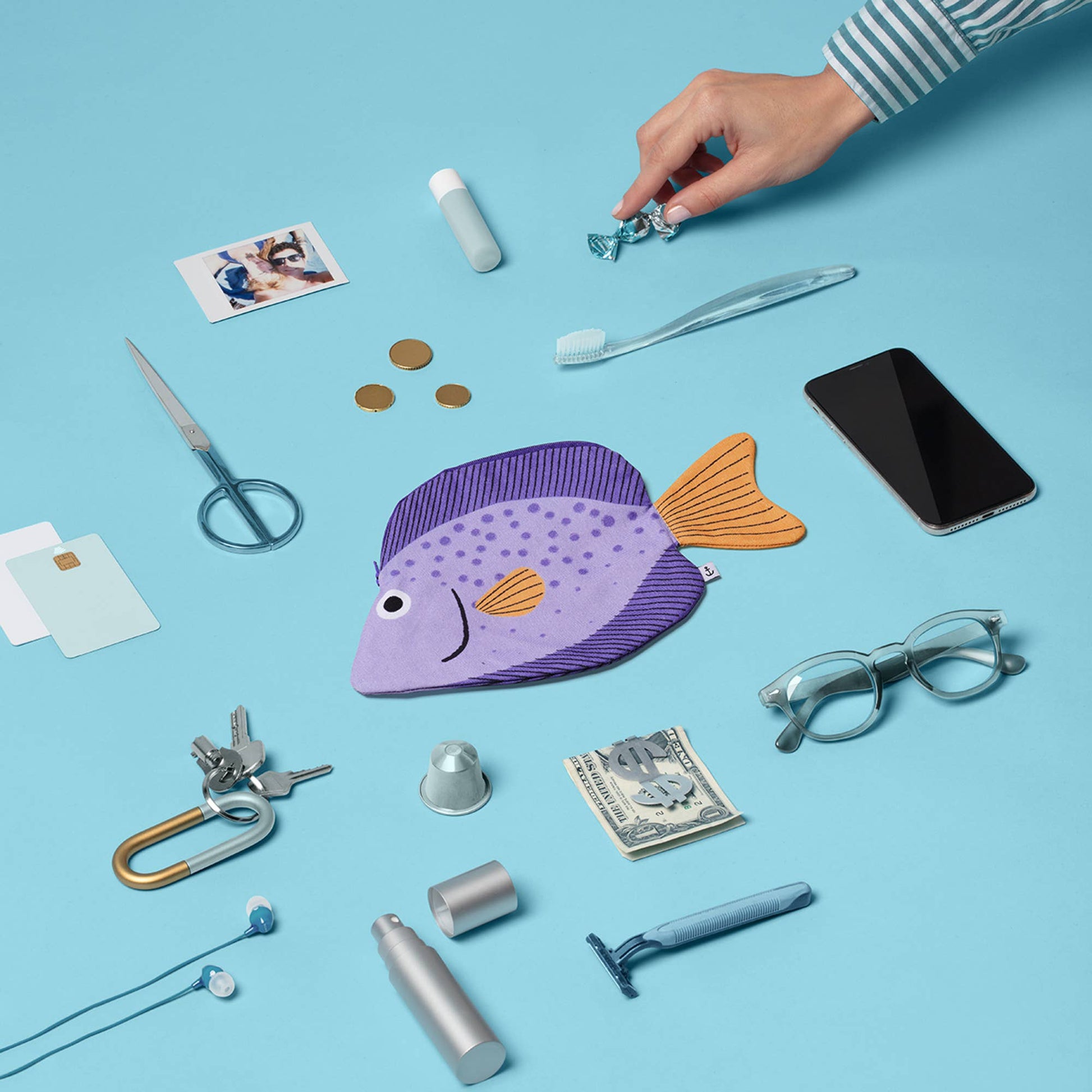 Fish-shaped pouch surrounded by various everyday items on a blue background