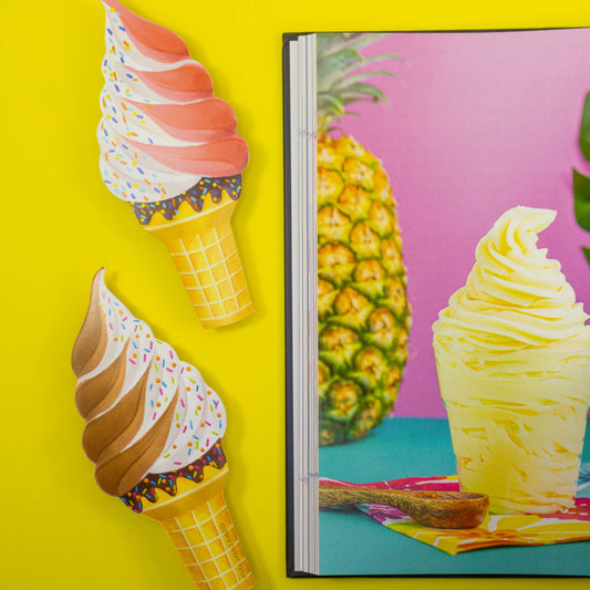 Colorful ice cream cone bookmarks on a yellow background with a magazine featuring a pineapple and pineapple soft serve.