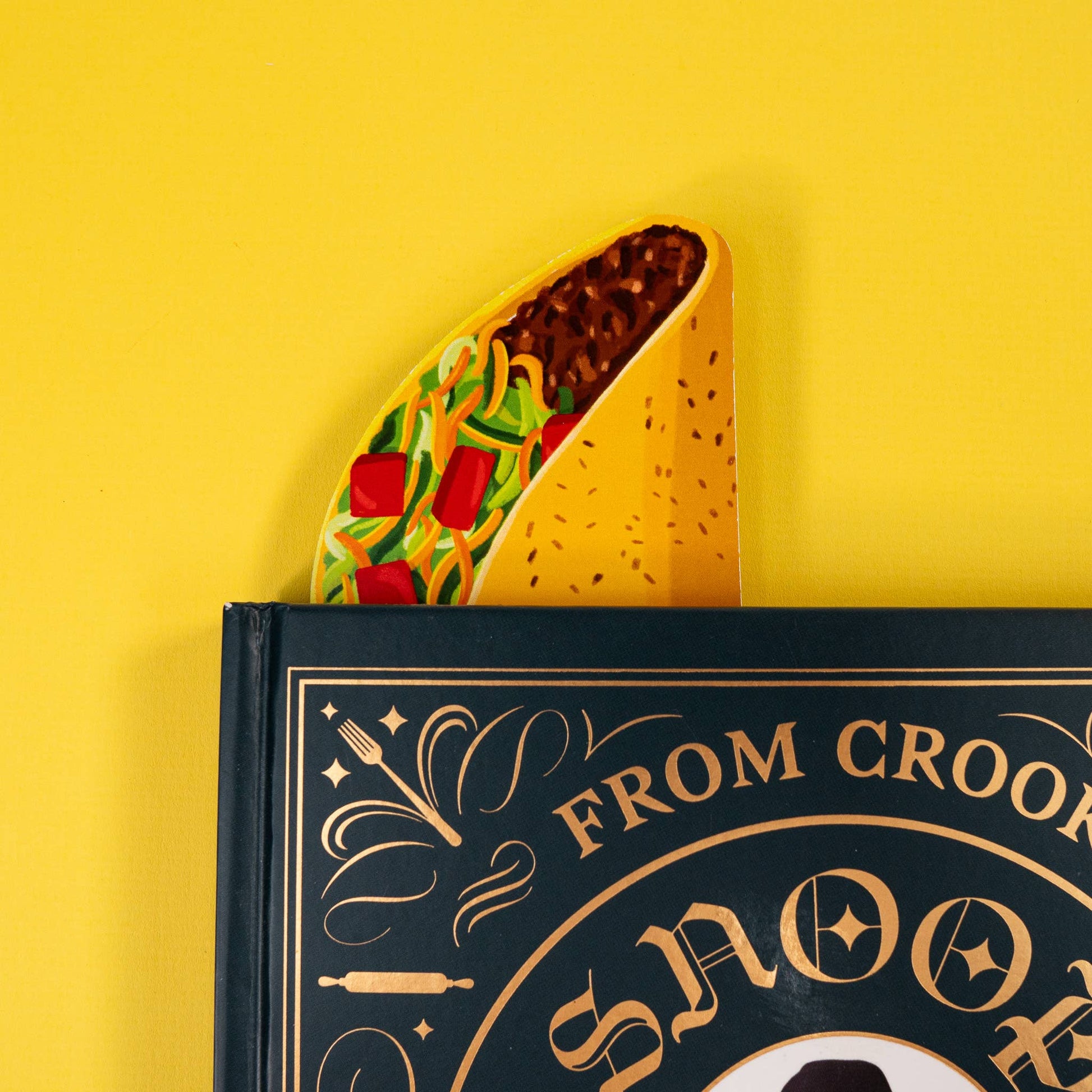 Taco-shaped bookmark pictured inside of a book against a yellow background