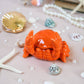 Orange crab-shaped object on a decorative surface with pearls and starfish