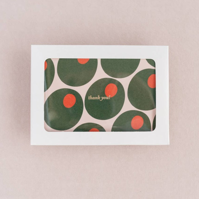Thank you card with the words in gold foil. Pattern of green olives stuffed with pimentos. Cards are shown in a white box with a transparent window.