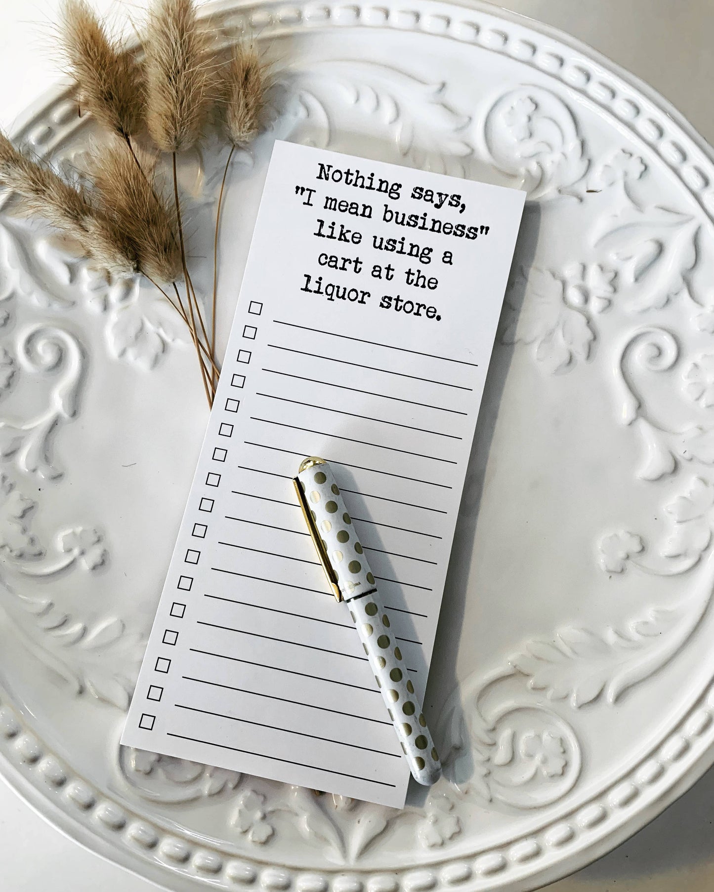 Liquor store list notepad on white platter with a pen 