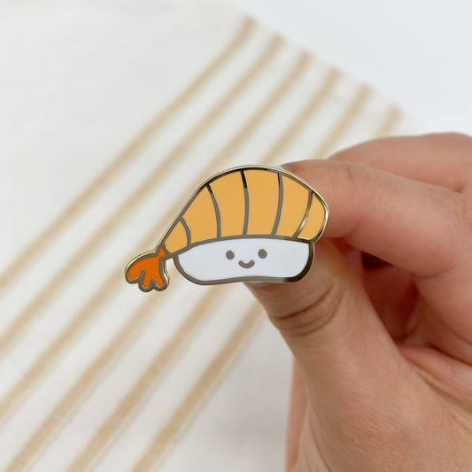 ebi sushi enamel pin with a smiley face on it