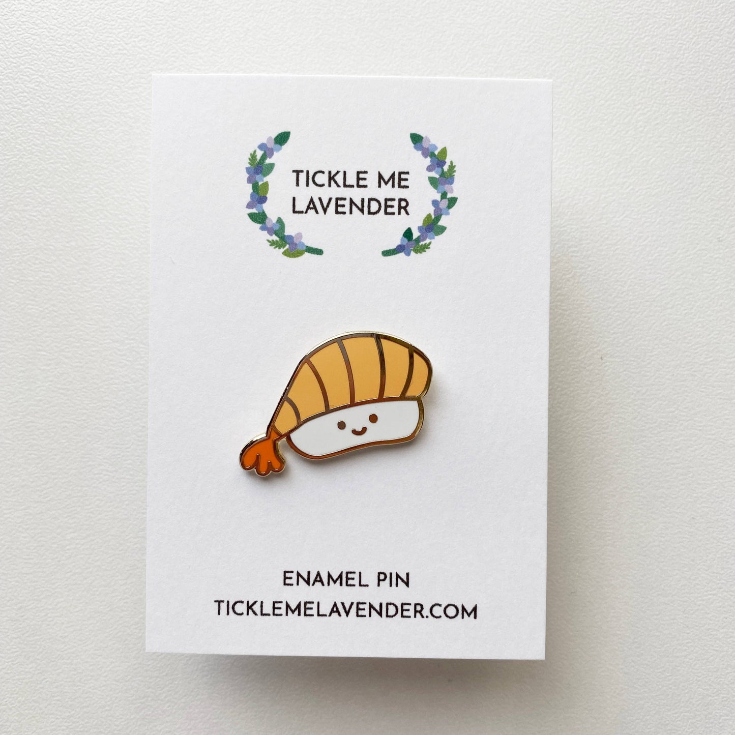 smiley faced ebi sushi enamel pin on white card backing 