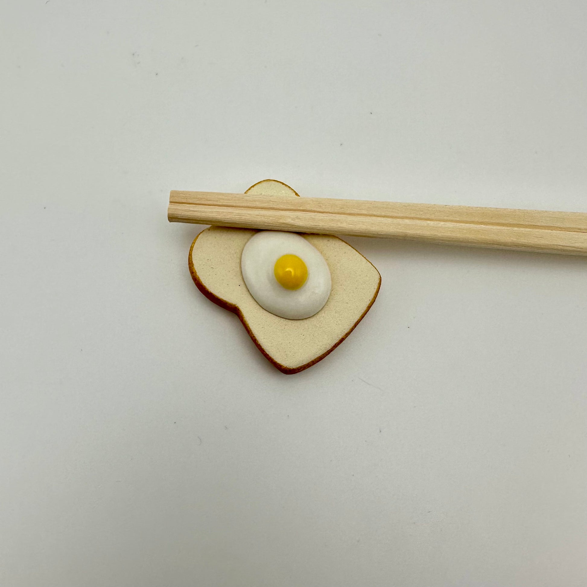 fried egg on toast ceramic chopstick holder with chopsticks on it 